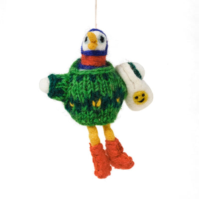 A handmade felted wool bird ornament hanging by a white string. The bird is wearing a green knitted sweater with yellow accents, a blue and red striped neck, yellow legs, and red boots, and has a white wing with a yellow smiley face.