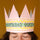 Person wearing a pink paper crown with 'Birthday Queen' text on a brown background
