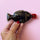 A hand holds Fish shaped soy sauce bottle inspired hand warmer with gold foil details.