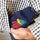 A hand holds a navy blue reusable mini hand warmer featuring an embroidered Woodstock wearing a red coat and green hat tucked inside a black and white checkered shirt pocket.